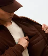 Campera bomber de pana color marrón, con cuello polo, cierre frontal con cremallera y puños y bajo elásticos.