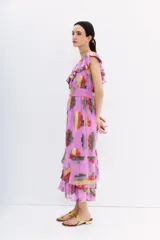 Vestido midi sin mangas, color lila, con escote en V adornado con volados y cinturón a tono. Presenta un estampado floral en jacquard de lurex multicolor con tonos rojos, amarillos y plateados.