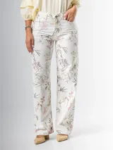 Pantalón wide leg de denim rígido con estampado floral chintz en tonos amarillo y rosa pastel sobre base blanca.