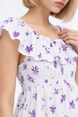Vestido largo de algodón blanco con estampado floral en tonos violeta, diseño holgado, escote bote con volados y detalle fruncido en el pecho.