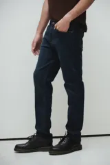 Jeans de tiro medio, corte regular, color azul oscuro, con lavado stone wash y bigotes láser.