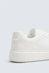 Zapatilla de cordones monocolor blanca, con parte superior fabricada en combinación de piezas, horma redonda y suela con volumen.