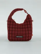 Cartera tipo hobo de diseño acolchado con costuras cuadradas, color bordó. Cuenta con un asa superior fija y un detalle de eslabones decorativos en un lateral. Incluye etiqueta con logo de la marca en la parte frontal.