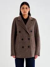 Tapado de lana marrón, de corte recto y ligeramente oversize, con diseño cruzado y doble botonadura. Presenta solapa clásica y bolsillos laterales a filete.