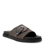 Sandalias chatas Miss Carol modelo Sage, color marrón, tipo slide con suela negra y una tira ancha en el empeine decorada con una gran hebilla metálica plateada de estilo western con grabados en relieve.
