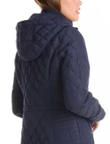 Campera capitoneada de corte clásico, con cuello alto, capucha desmontable y cierre frontal con broches a presión dorados. Presenta cordón de ajuste en la cintura con terminales metálicas y bolsillos frontales con broche.