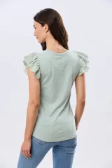 Remera de algodón color beige, de manga corta con volados de broderie, escote redondo y cuerpo liso.