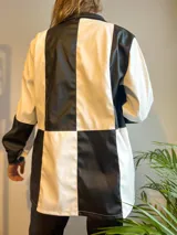 Campera con cierre frontal, diseño color block blanco y negro, cuello camisero y bolsillos laterales.