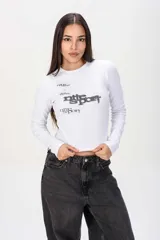 Remera blanca de manga larga y corte ajustado, confeccionada en tejido rib con diseño estampado en el frente.