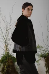 Chaleco de piel sintética en color chocolate, con cierre frontal y detalles de cuero en los bordes. Presenta un diseño de cuello solapa y ajuste lateral con hebillas.