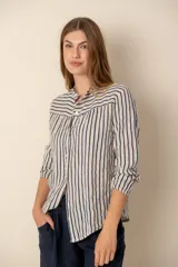 Camisa de lino a rayas verticales azules y blancas, con cuello mao, manga larga con puño elástico y cierre frontal con botones.