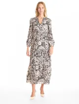 Vestido maxi de satén con estampado floral en tonos negro y beige. Presenta escote en V, hombros fruncidos, mangas largas con puños elásticos y cintura con detalle de punto smock. La falda tiene un diseño escalonado con vuelo.