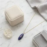 Collar de cadena fina con baño de oro y dije alargado de piedra lapislázuli con una pequeña circonia engastada en el centro.