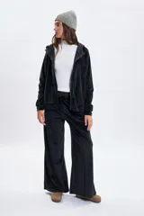 Campera de plush color negro con cierre frontal, capucha con cordones ajustables y mangas ranglan. Presenta un diseño cómodo y versátil con puños y ruedo acanalados.