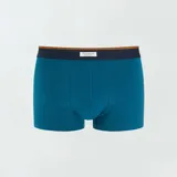 Pack de tres boxers de algodón elastizado, uno liso color celeste, uno con estampado geométrico azul oscuro sobre celeste y otro con estampado geométrico celeste sobre blanco. Todos tienen cintura elástica con logo de la marca.