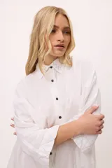 Vestido camisero negro de algodón, con mangas tres cuartos y cuello camisero. Presenta detalles de costura en zigzag color naranja en el cuello y en los puños.