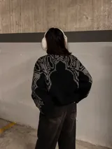 Sweater negro con cuello redondo y diseño geométrico en gris en la parte superior del pecho y hombros.