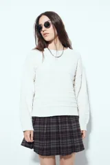 Sweater de punto color blanco con textura de líneas horizontales en relieve, cuello redondo, hombros caídos y mangas largas.