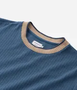 Remera de manga corta, color azul, con textura acanalada vertical. Presenta cuello redondo y puños contrastantes en color beige.
