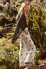 Pantalón color crema de tiro medio con cintura elástica ajustable y bolsillos delanteros. Presenta bordados florales en negro y corte ancho.