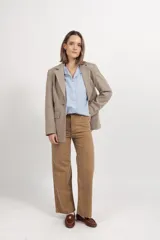 Blazer de paño fantasía en color beige, con solapas clásicas, cierre frontal de botones y dos bolsillos delanteros con solapa. Presenta una estructura entallada con forro interior.