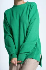 Sweater azul eléctrico de punto acanalado, con cuello redondo y mangas largas. Corte holgado con aberturas laterales.