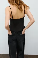 Top negro de escote en pico con tirantes finos ajustables, diseño entallado y cierre lateral con cremallera.