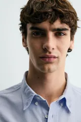 Camisa de corte regular fit confeccionada en tejido de algodón tipo Oxford. Presenta cuello abotonado, manga larga con puños abotonados, bolsillo frontal en el pecho y cierre de botonadura central.