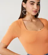 Blusa de punto acanalado color naranja, con escote cuadrado y mangas cortas con volados en los puños.
