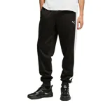 Pantalón deportivo Puma modelo Essentials T7, color verde con franjas laterales blancas y logo de la marca bordado en el frente. Cuenta con cintura elástica, bolsillos laterales con cierre y puños acanalados en los tobillos.