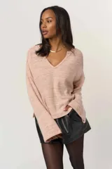 Sweater de tejido liviano y suave, color rosa claro jaspeado, con escote en V y mangas largas de corte relajado.