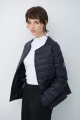 Campera acolchada tipo puffer en color beige, con diseño sin cuello y cierre frontal con botones a presión.