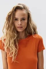 Remera de punto acanalado color naranja, de manga corta, cuello redondo y corte entallado.