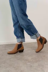 Bota corta de cuero color marrón con elásticos laterales, taco bajo y punta redondeada.