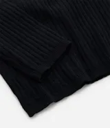 Blusa negra de punto liviano con textura acanalada, escote en pico y mangas largas.