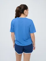 Remera de fútbol Umbro del Club Nacional de Football, modelo Bink para mujer. Diseño azul oscuro con cuello redondo y mangas cortas, con logo de Umbro en el pecho derecho y escudo del club en el pecho izquierdo.