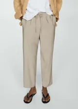Pantalon de corte recto y diseño jogger, confeccionado en tejido fluido color beige. Presenta cintura elástica con cordón ajustable, tiro alto y bolsillos laterales.