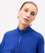 Campera de punto pesado color azul, con cuello alto, cierre frontal con cremallera y bolsillos delanteros con solapa y botones. Cuenta con mangas largas y puños y bajo acanalados.