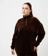 Campera deportiva de plush color marrón, con cuello alto, cierre frontal parcial y mangas largas con puños elásticos. Presenta una textura acanalada y un corte holgado.