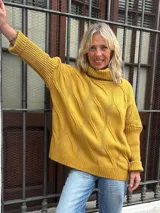 Polera de tejido de punto color amarillo mostaza, con diseño de ochos, cuello alto y corte oversize.