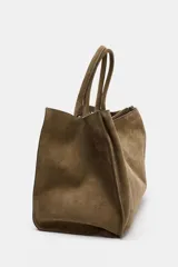 Bolso de hombro formato maxi city confeccionado en piel de gamuza color marrón. Cuenta con doble asa de hombro, doble compartimento interior y cierre mediante clip metálico y cremallera.