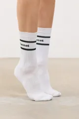 Medias altas de algodón con diseño deportivo, presentan dos líneas horizontales negras y el logo de la marca en la parte superior.