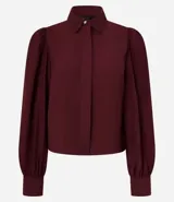 Camisa celeste de crepé con cuello inglés, manga larga abullonada y abotonadura frontal.