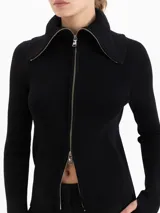 Cardigan de tejido de punto fino con silueta ajustada, cuello alto y cierre frontal de doble camino. Presenta mangas largas con aberturas para los pulgares.