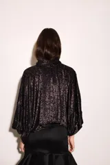 Camisa negra con estampado de hojas en relieve, cuello camisero, mangas anchas y corte cropped.