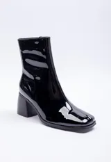 Botín negro de charol con caña media, punta cuadrada, cierre lateral y tacón bloque.