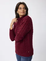 Sweater de tejido grueso con textura trenzada, cuello alto y mangas largas.