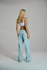 Jean wide leg de mujer en denim azul claro, con efecto desgastado, aberturas y aplicaciones de pedrería brillante distribuidas a lo largo de la silueta.