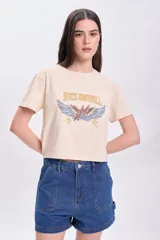 Remera color crudo de corte cropped, con mangas cortas y estampa frontal con la frase 'Rock and Roll' y un rayo alado.