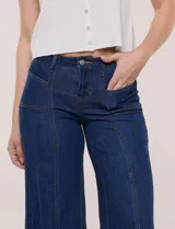Jean wide leg de tiro alto en denim azul claro, con calce ajustado en la cadera, costuras verticales frontales y bolsillos estilo carpintero.